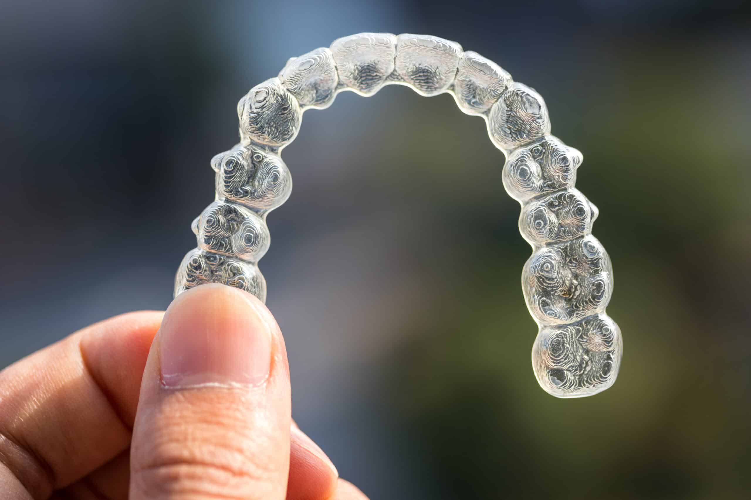 Holding,Invisalign,Braces,On,Bokeh,Background